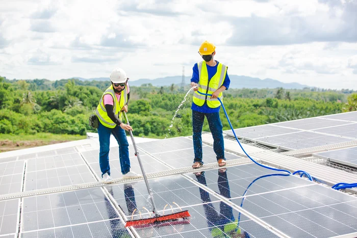 professional-worker-cleaning-solar-panels-with-bru